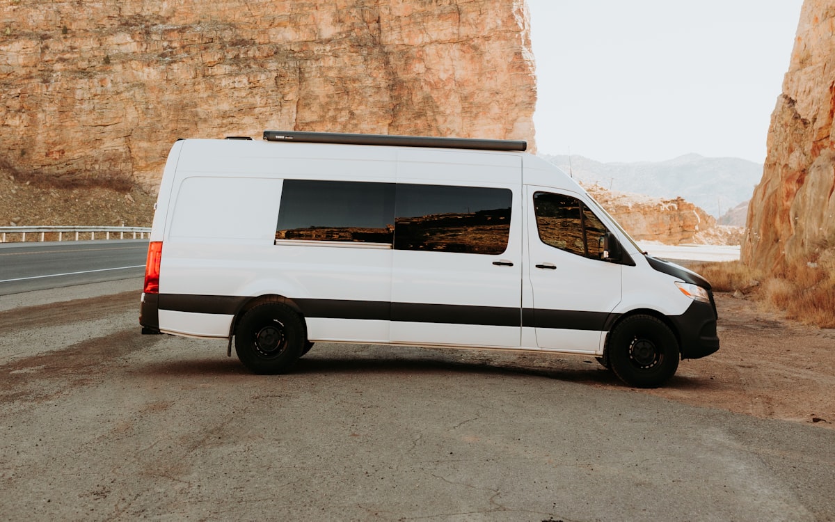 White Mercedes-Benz Sprinter passenger van parked on a canyon road