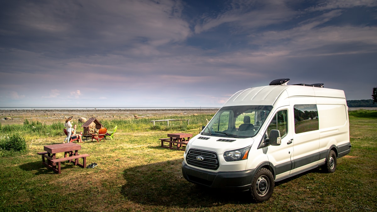 White high-roof Ford Transit passenger van parked at dusk